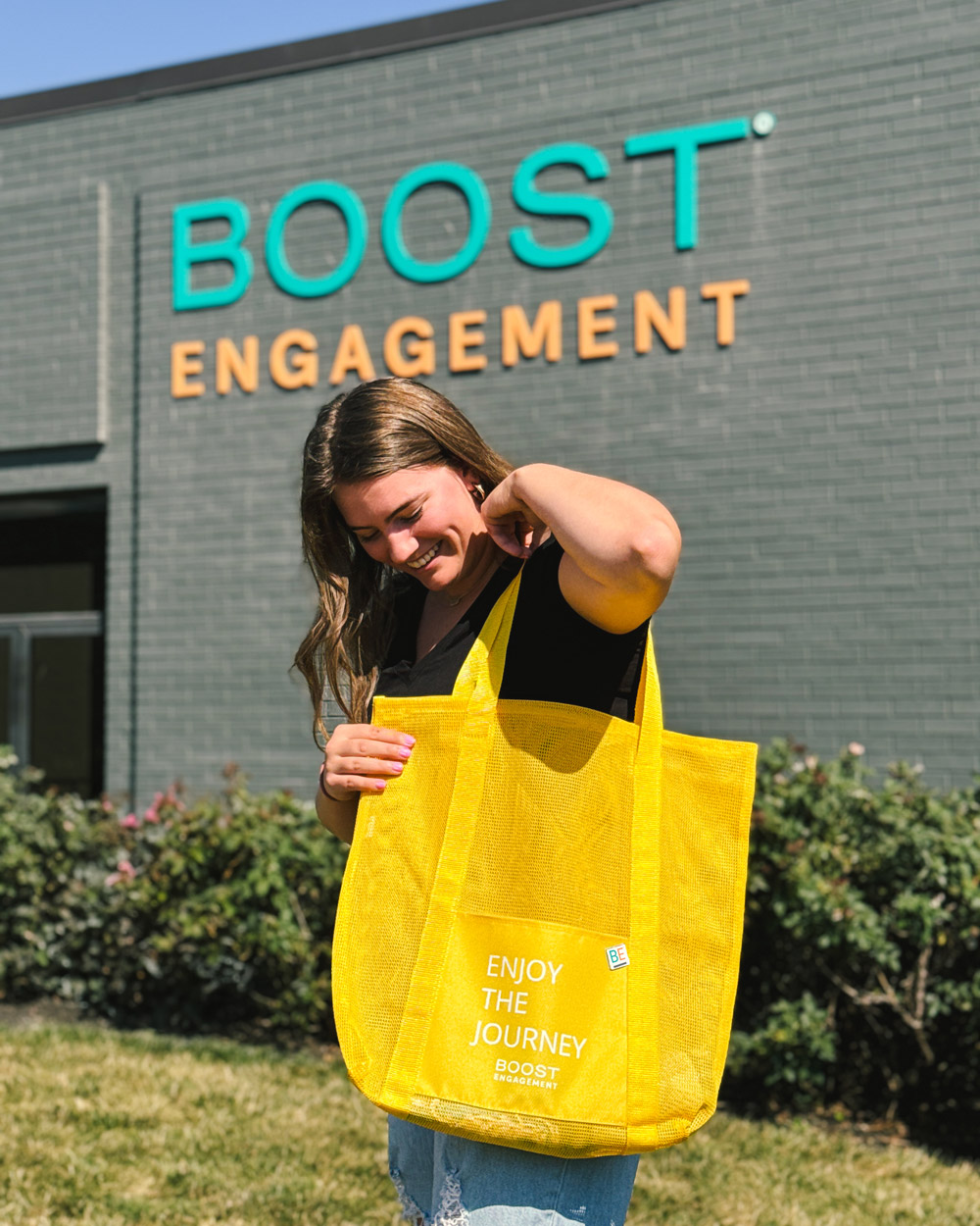 Woman standing outside with Boost Engagement branded tote bag merchandise