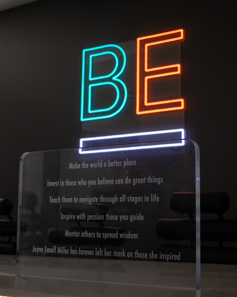 BE neon sign with plaque that summarizes Boost's mission and vision